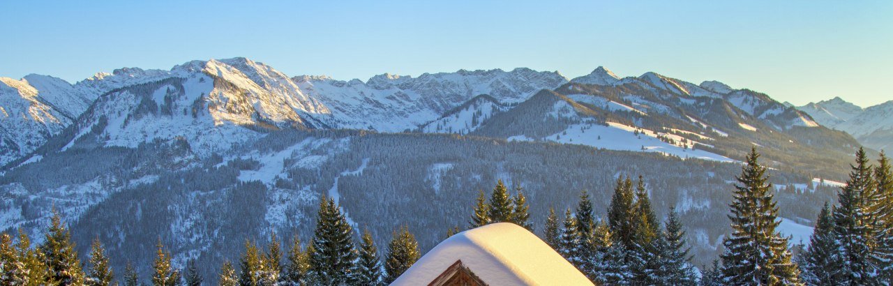 Verschneite Hütte vor Allgäuer Winterpanorama © Dominic Ultes