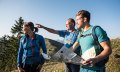 Wanderer steigen einen Bergpfad hinauf, umgeben von malerischen Alpenlandschaften und grünen Wiesen. Im Hintergrund sind sanfte Berggipfel und Wolken zu sehen. © Tourismus Hörnerdörfer, F. Kjer